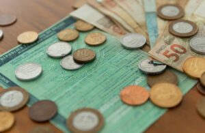 Cédulas e moedas brasileiras sobre documento de veículo, representando o pagamento do IPVA