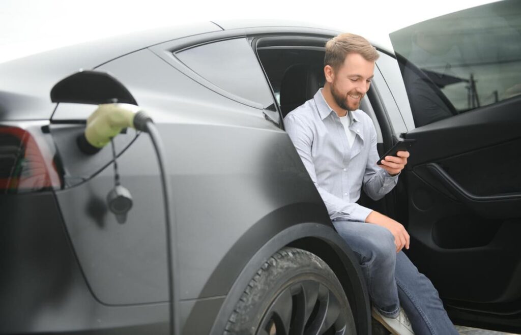 Proprietário carregando carro elétrico, beneficiado por regras de isenção após a IPVA 2026 consulta.