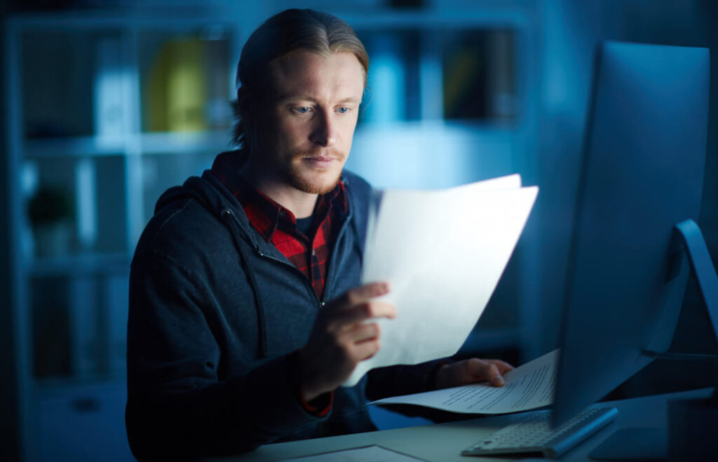 Homem analisando débitos no computador para evitar juros ao pagar multas de trânsito atrasadas.