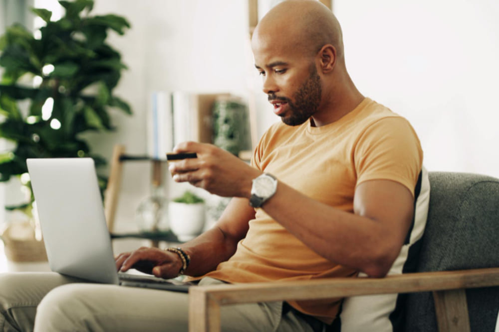 Homem utilizando computador para pagar ipva detran com segurança.