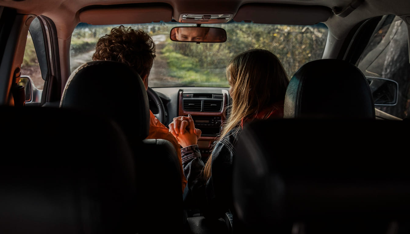 Família relaxada dentro do carro em uma rodovia ao pôr do sol, viajando nas férias de fim de ano sem preocupações com pedágios graças ao Sem Parar.